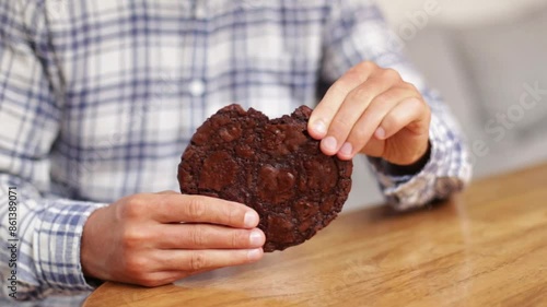 A man in a plaid shirt breaks off a piece of chocolate chip cookies. The concept of delicious oatmeal cookies with chocolate chips photo