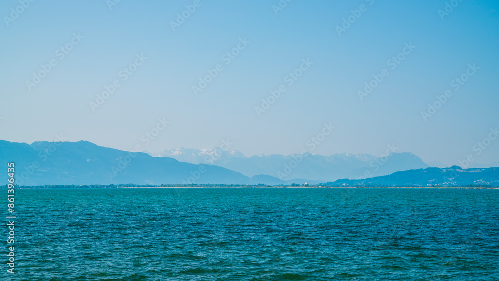 Germany, Snow covered mountains nature landscape behind water of bodensee lake, panorama view from lindau to swiss and austrian coast on misty day