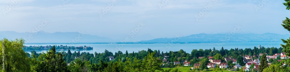 Germany, Lindau, XXL aerial panorama view above lindau island, bad schachen tower, lighthouse, city, tree tops and silent lake water early morning after sunrise, foggy view to swiss alps