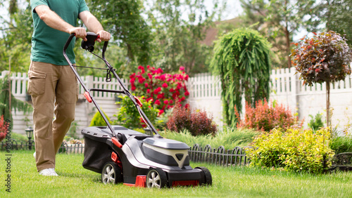 Man using lawnmower for mowing grass on his backyard, cropped shot, free copy space