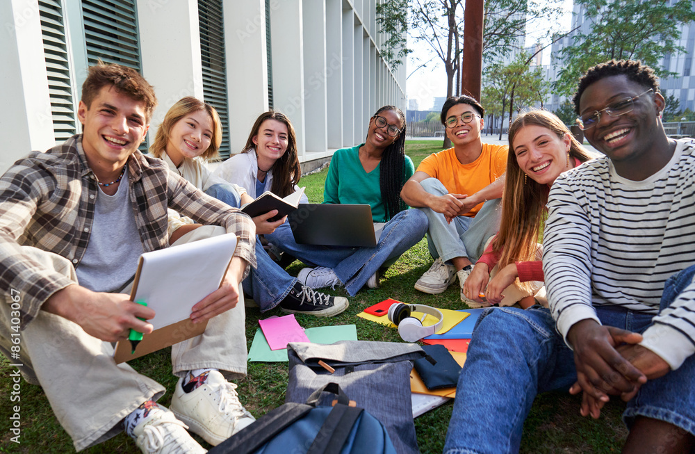 Portrait of a multiethnic group of student friends outside university campus looking at camera smiling, sitting on the grass gathered to study together. Portrait of a multiethnic group of student friends outside university campus looking at camera smiling, sitting on the grass gathered to study together.