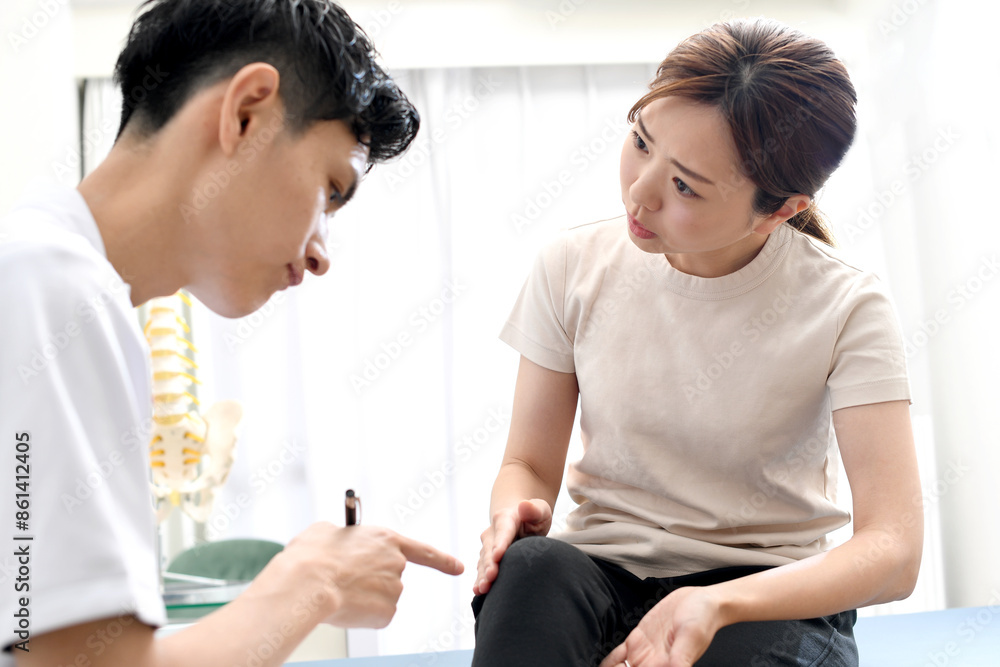 脚の痛みで悩む女性患者と話す白衣姿の男性 脚の痛みで悩む女性患者と話す白衣姿の男性