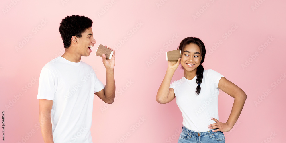 Communication and fun. Teen couple talking through tin can phone, pink background Communication and fun. Teen couple talking through tin can phone, pink background