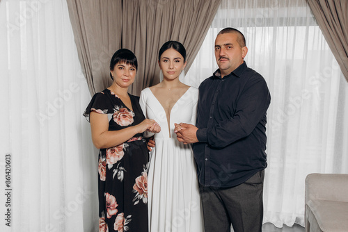 A woman in a white dress stands between two other people photo
