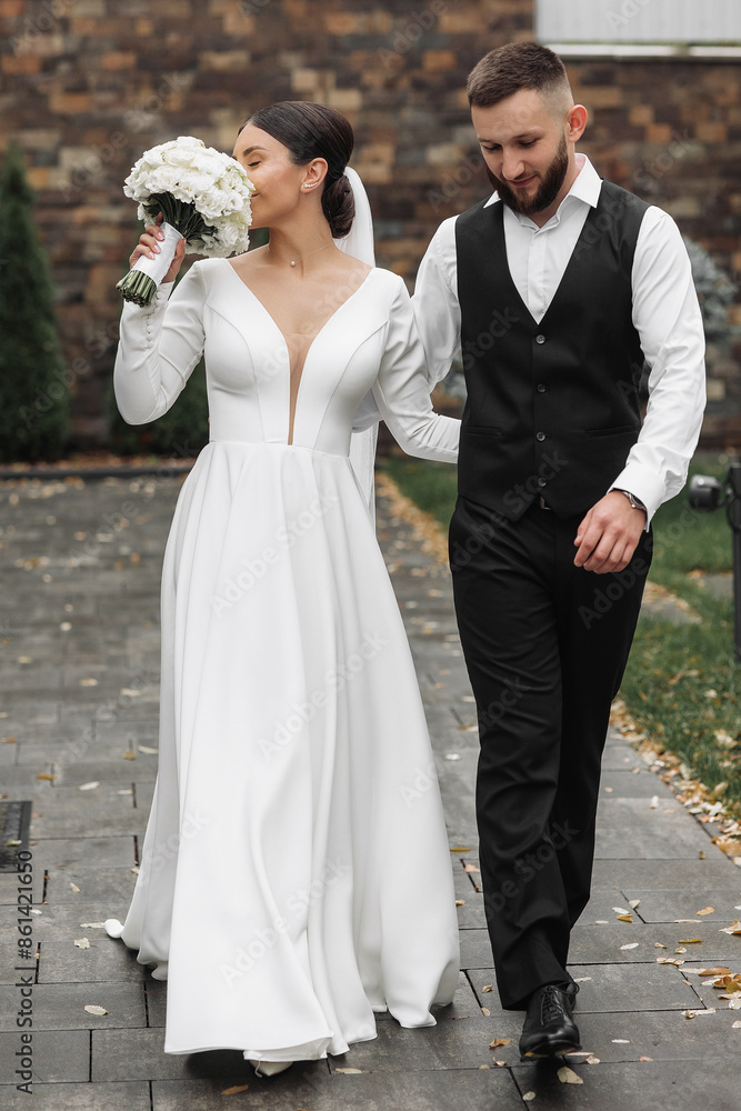A bride and groom are walking down a path, the bride is holding a bouquet of flowers A bride and groom are walking down a path, the bride is holding a bouquet of flowers