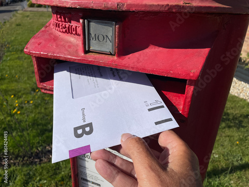 Bild auf Leinwand An Envelope B for the United Kingdom General Election postal vote can be seen with a hand putting it in a red post