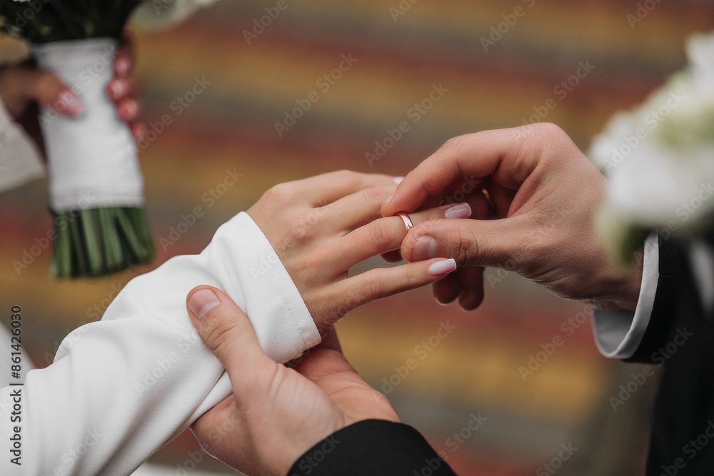Fototapeta premium A man and woman are getting married and the man is putting a ring on the woman's finger