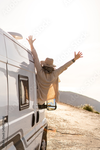 Woman enjoying the moment from a campervan at sunset