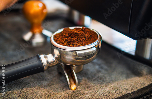 Close-up of ground coffee in portafilter or portable coffee filter handle and ground coffee for a coffee making machine on coffee shop photo