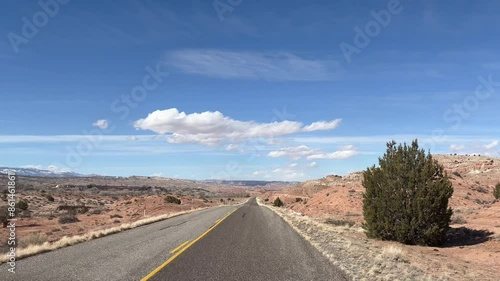 Point of View POV driving shot along the empty Burr Trail road, a scenic byway in Capitol Reef National Park, Utah. The road winds through a stunning, barren desert landscape of red rock - USA