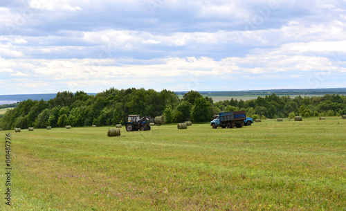 a field with a tractor and a truck with a sky background 