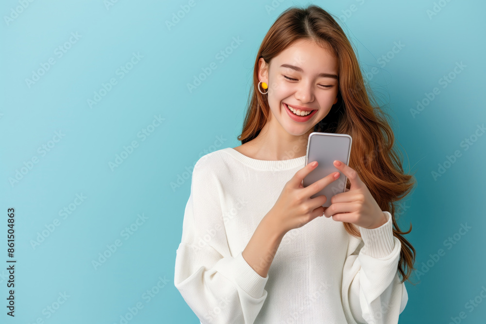 pretty woman smiling happily while reading message on her smart phone on isolate blue background pretty woman smiling happily while reading message on her smart phone on isolate blue background
