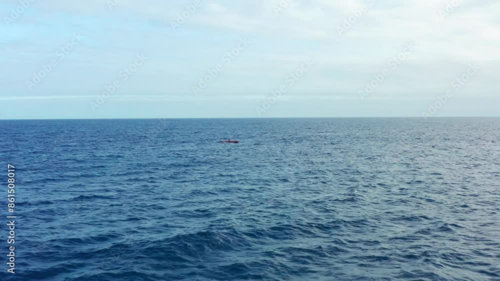 Drone flying view low angle over ocean and outrigger canoe alone rowing on blue sea in Hawaii. Sport activity on open sea. Hawaiian outrigger paddling and canoes Drone flying view low angle over ocean and outrigger canoe alone rowing on blue sea in Hawaii. Sport activity on open sea. Hawaiian outrigger paddling and canoes