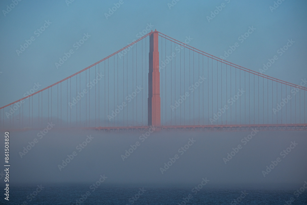 World famous red steel suspension bridge in San Francisco port entrance with Golden Gate State park nature lands hidden in cloud mist fog bank with clear sky pilars World famous red steel suspension bridge in San Francisco port entrance with Golden Gate State park nature lands hidden in cloud mist fog bank with clear sky pilars