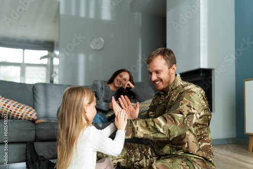 Obraz na plátne Rejoicing soldier man playing with cute little daughter at home