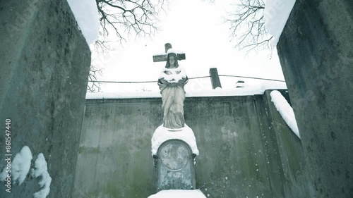 VILNIUS, LITHUANIA - 01 10 2024. An old snowy Mary statue at the Rasos XIX century cemetery. photo