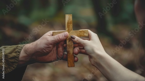Christian proselytizing, hands of Christian man holding and passing wooden cross to woman's hands, great commission concept