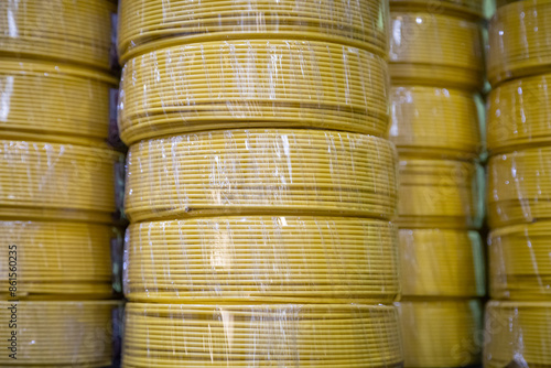 Stacks of yellow electric wire tubing coils, wrapped in protective plastic, arranged in vertical rows.