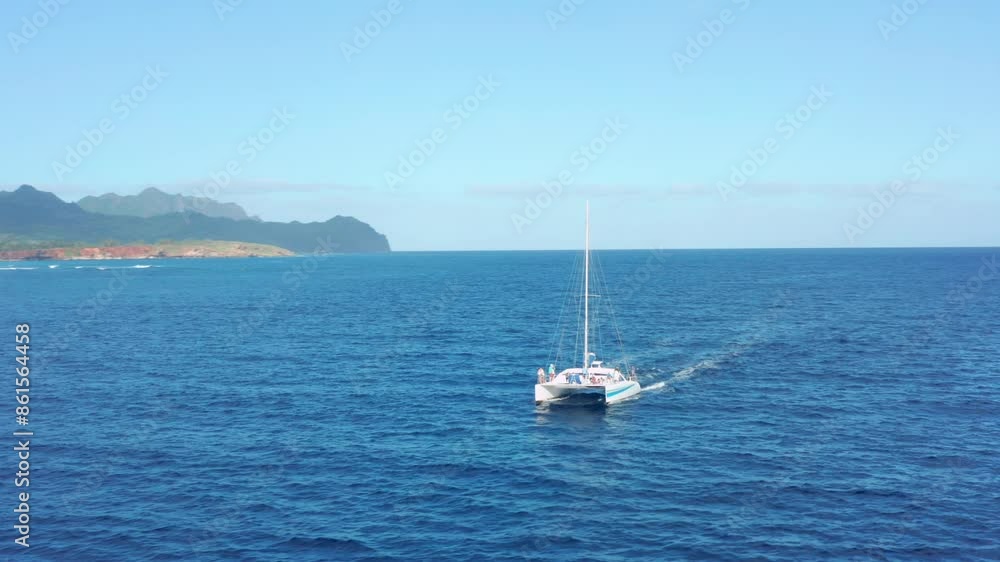 Sailing in Hawaii. Aerial view of west coast island of Kauai with mountains background and calm clear blue Pacific Ocean. Aerial drone camera passing sail boat on clear sunny day Sailing in Hawaii. Aerial view of west coast island of Kauai with mountains background and calm clear blue Pacific Ocean. Aerial drone camera passing sail boat on clear sunny day