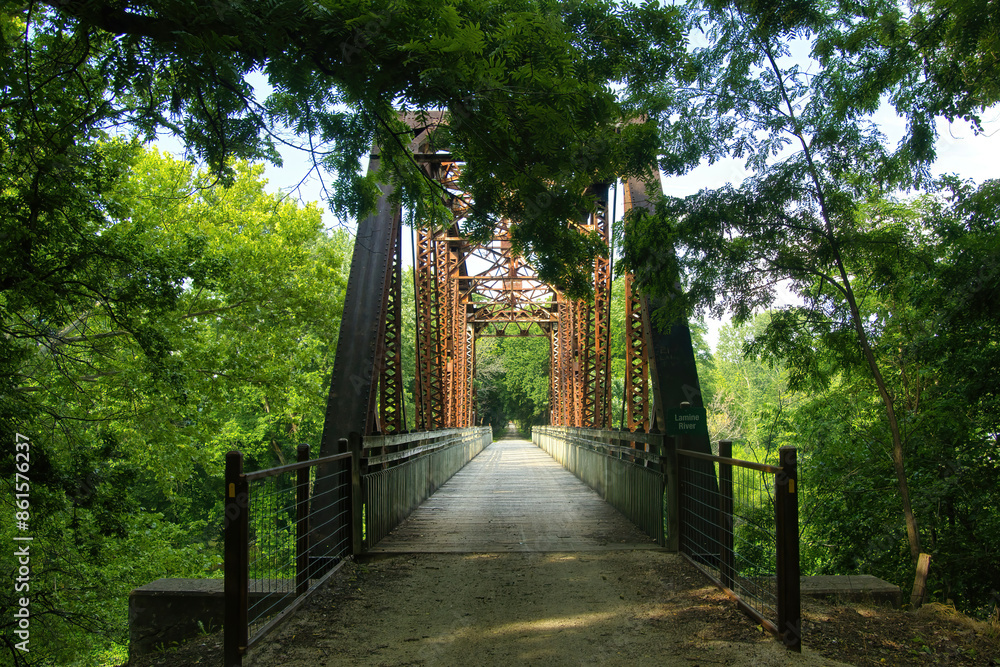 Summer landscape of the Katy Trail passing over an old railroad trestle in a lush green forest, near Sedalia, Missouri. Summer landscape of the Katy Trail passing over an old railroad trestle in a lush green forest, near Sedalia, Missouri.