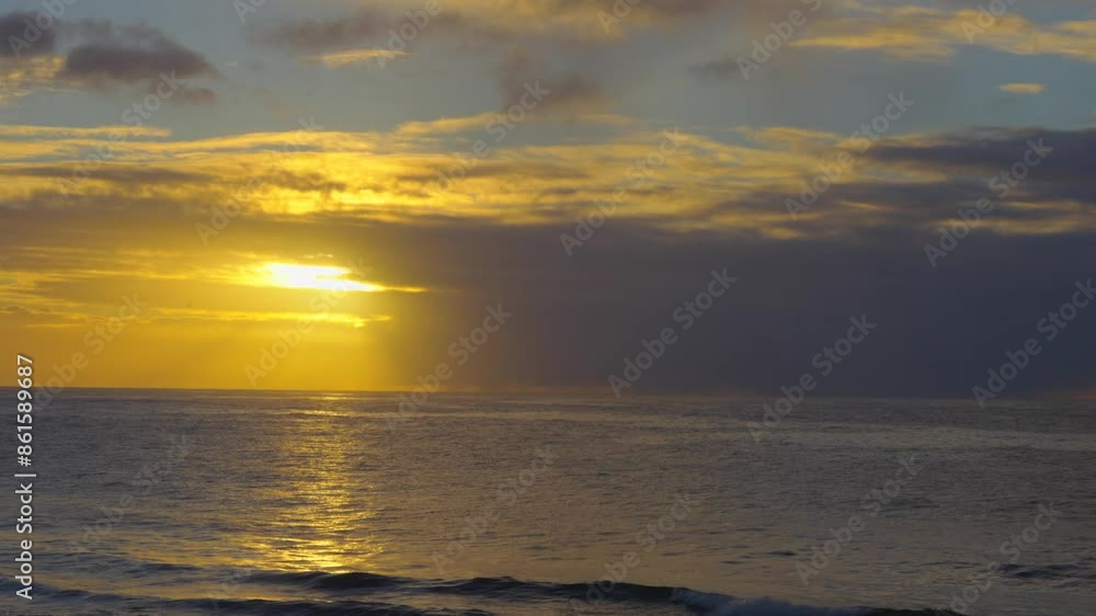 Sunrise at horizon over ocean sea. Big raincloud moving over sun. Small waves on surface in slow motion video Sunrise at horizon over ocean sea. Big raincloud moving over sun. Small waves on surface in slow motion video