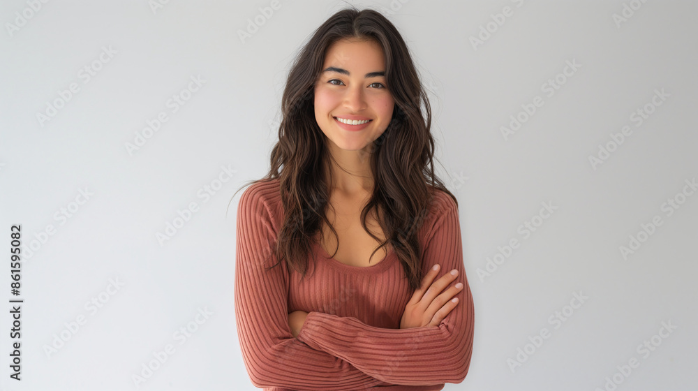 Smiling young woman with long dark hair and arms crossed, wearing a casual brown top against a light background Smiling young woman with long dark hair and arms crossed, wearing a casual brown top against a light background