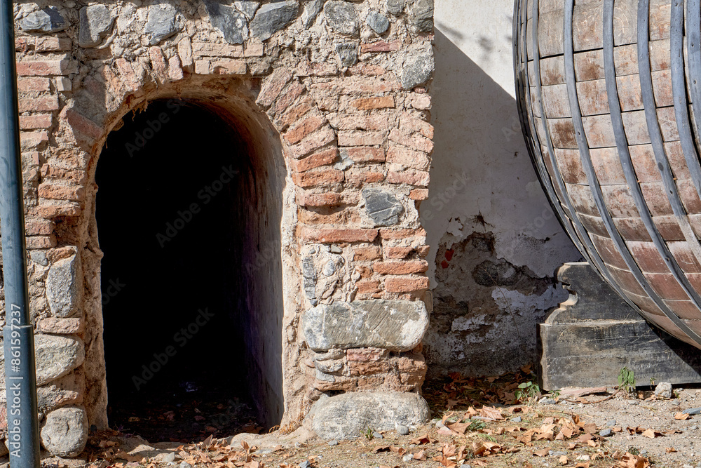 entrance to a decommissioned wine cellar with an old barrel next to it entrance to a decommissioned wine cellar with an old barrel next to it