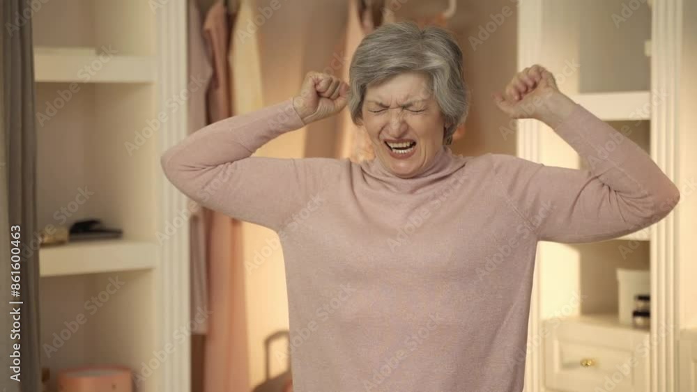 Elderly woman in a closet throwing clothes around while getting dressed. She appears to be frustrated and in a hurry Elderly woman in a closet throwing clothes around while getting dressed. She appears to be frustrated and in a hurry