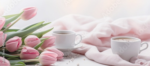 Spring-themed setup featuring pink tulips, chocolates, a coffee cup, and a candle on a white surface, conveying a cozy spring concept with space for text or images. with copy space image photo