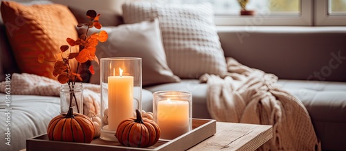 Create a warm autumn ambiance with a hygge home decor setup featuring orange and gray pumpkins and lit candles on a tray placed on a coffee table in the living room, with clear focal point. Include photo
