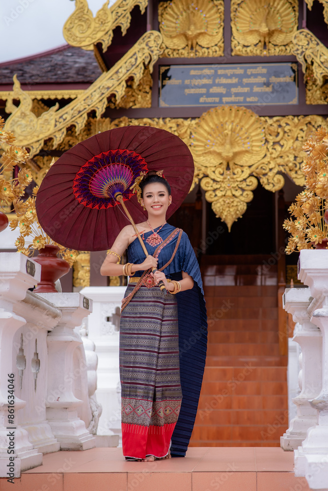 Fototapeta premium Woman wearing Thai dress visits beautiful temple in Thailand.