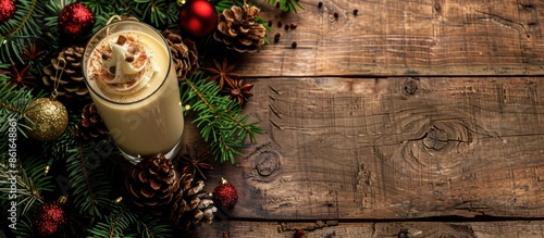 A Christmas-themed Tom and Jerry cocktail presentation on a rustic wooden background with christmas decorations, showcasing a whipped cream eggnog with spices, dairy milk beverage, and ample copy photo