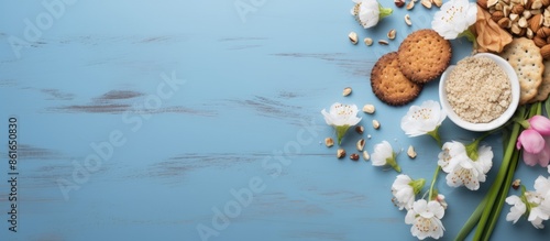 Top view of a Seder Pesach spring holiday background featuring a Jewish holiday Passover theme with matzah, nuts, and tulip flowers on a blue table, ideal for a greeting card, with room for text or photo