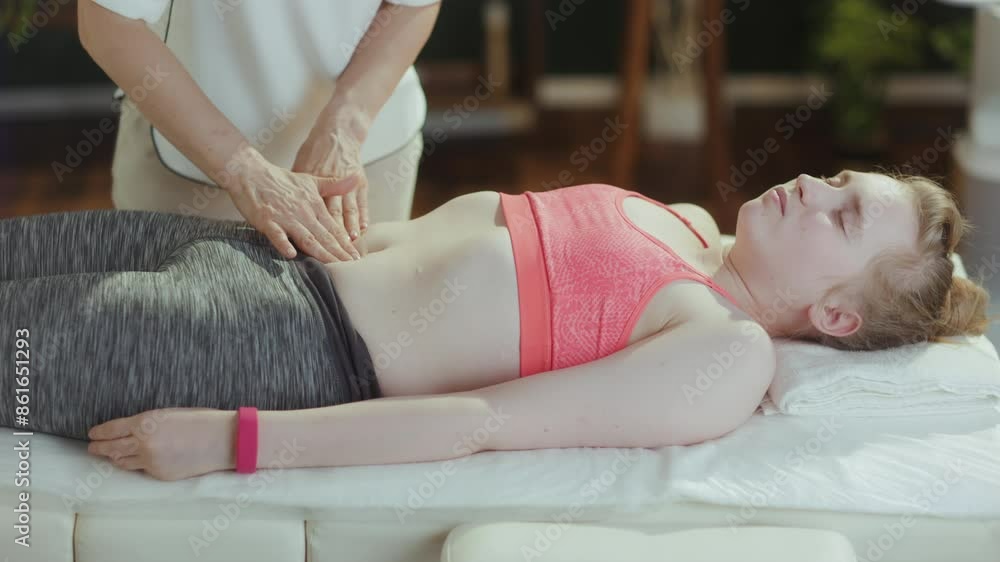 Healthcare time. female medical massage therapist in massage cabinet with teenage client doing checkup on massage table.