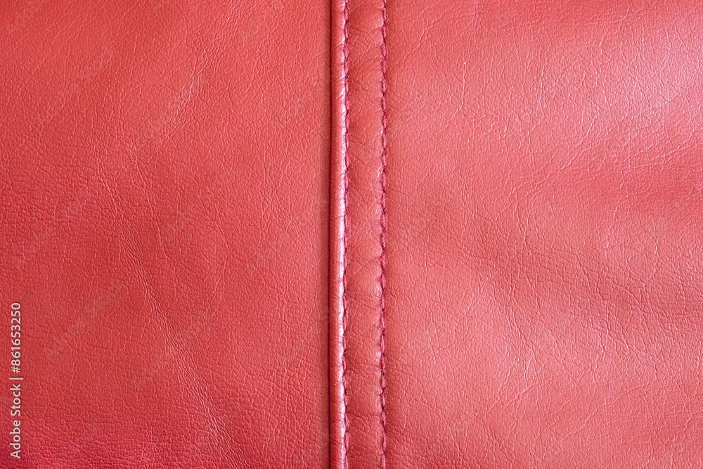 Fototapeta premium A close-up view of a red leather, highlighting its rich texture and the meticulous stitch work that runs down its spine and a vibrant red hue exudes luxury and the fine grain details. Clothes texture