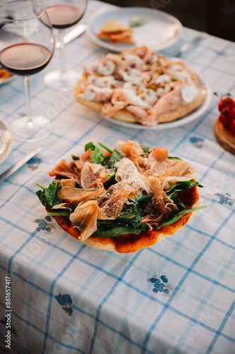 Outdoor Dining table of Homemade Pizza and Fresh Ingredients with wine and cutlery. Italian dream countryside romantic dinner 