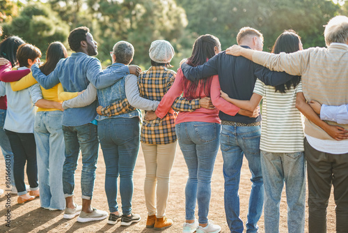 Group of multiracial people hugging each other at city park - Back view of multi generational community outdoor - Humanity concept photo