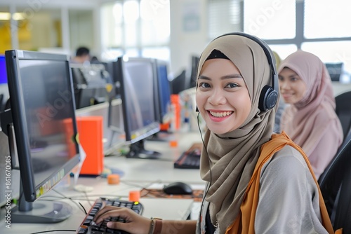 Smiling malay call center agents working at computer