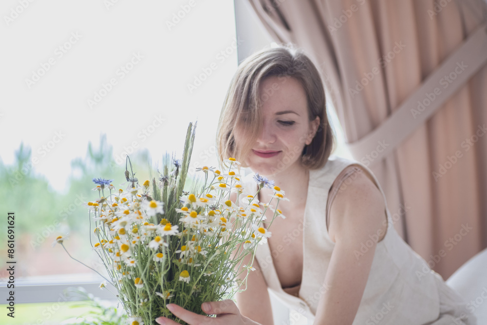 Beautiful woman at home with modern renovation in warm colours is puts a bouquet of fresh flowers in a vase. Beautiful woman at home with modern renovation in warm colours is puts a bouquet of fresh flowers in a vase.