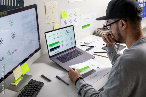 Fotografía Asian graphic designer making notes on logo designs, using computers, designing logos, and showcasing the corporate identity and logo design process