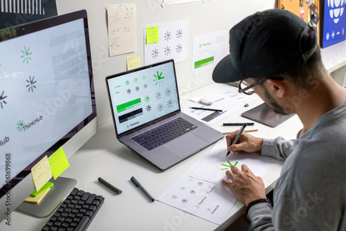 Asian graphic designer making notes on logo designs, using computers, designing logos, and showcasing the corporate identity and logo design process. photo