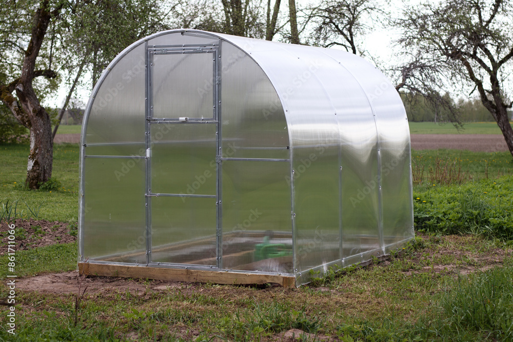 transparent plastic greenhouse on a metal frame in the garden
transparent plastic greenhouse on a metal frame in the garden
