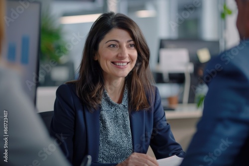 A woman sits at a table with a man in a suit, discussing business matters