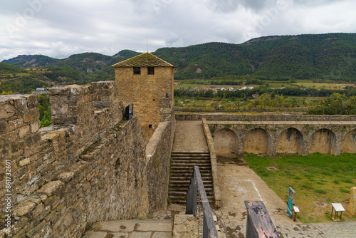 Las murallas del castillo de Ainsa, Aragón, España, ofrecen una vista impresionante de la fortaleza medieval con sus robustas paredes de piedra y una torre de vigilancia.  photo