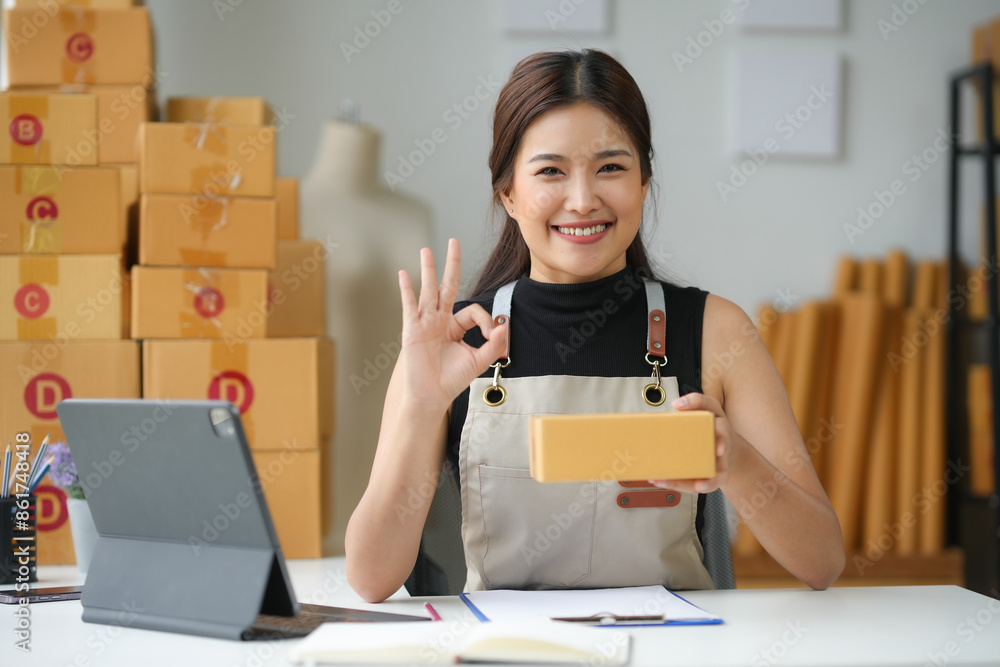 Asian sme business owner holding package and making ok sign Asian sme business owner holding package and making ok sign