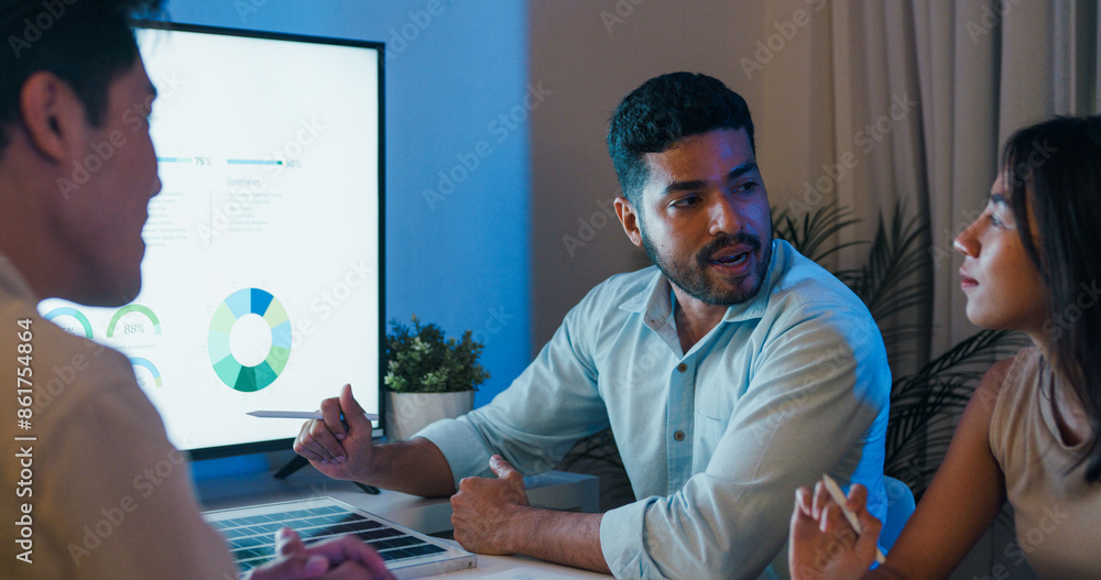 © tirachard - Group diverse Asia businesspeople talk ESG strategies risk management solar panel workshop night, SDGs, global warming, green finance and investment and net zero waste in boardroom training building.