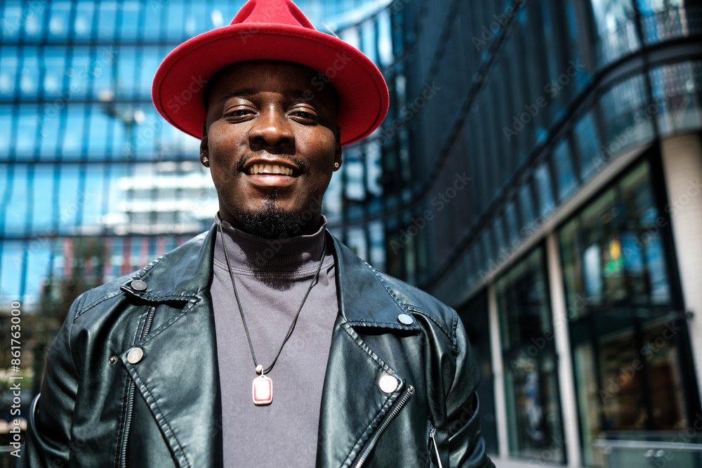 Smiling man wearing a red hat is looking at camera standing in a business environment outside. Smiling man wearing a red hat is looking at camera standing in a business environment outside.