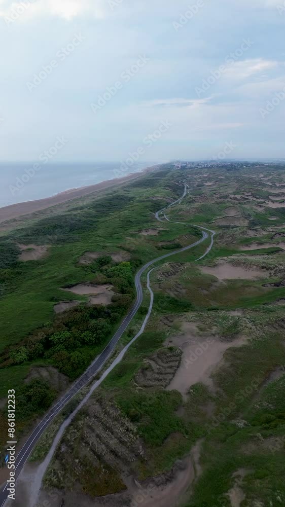 A beautiful bike path shot from above. Flying a quadcopter over a bike path. Green grass and bushes near the beach in the Netherlands. Sand dunes. Beautiful flight in summer over the beach. A beautiful bike path shot from above. Flying a quadcopter over a bike path. Green grass and bushes near the beach in the Netherlands. Sand dunes. Beautiful flight in summer over the beach.