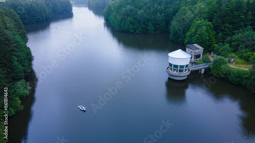 Aerial view of a lake in the mountains with a rowing boat. Photography was taken from a drone at a higher altitude with camera lowered for a top view of the lake. photo