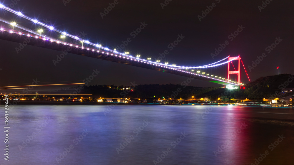 Fototapeta premium The illuminated bridge on the Bosphorus strait late at night in Istanbul with light trails from the ships